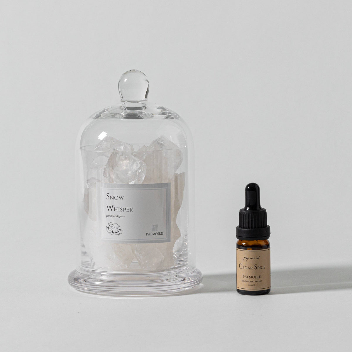 Glass jar with decorative items and a small bottle on a light gray background