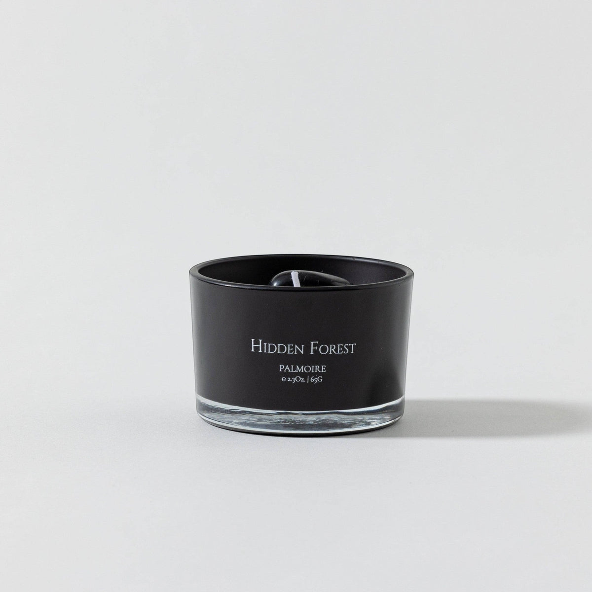 FULL MOOD Hidden Forest soy wax candle in a black glass jar with embedded black gemstones on a neutral background.