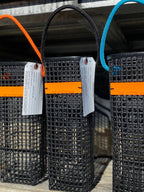 Three black woven bags with colorful straps hanging on a metal railing.