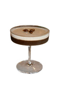 Cocktail in a glass with a creamy texture and chocolate elements on a marble surface.