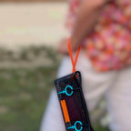 FULL MOOD The Clutch oyster bag in black mesh with orange wrist strap and bright blue circular accents