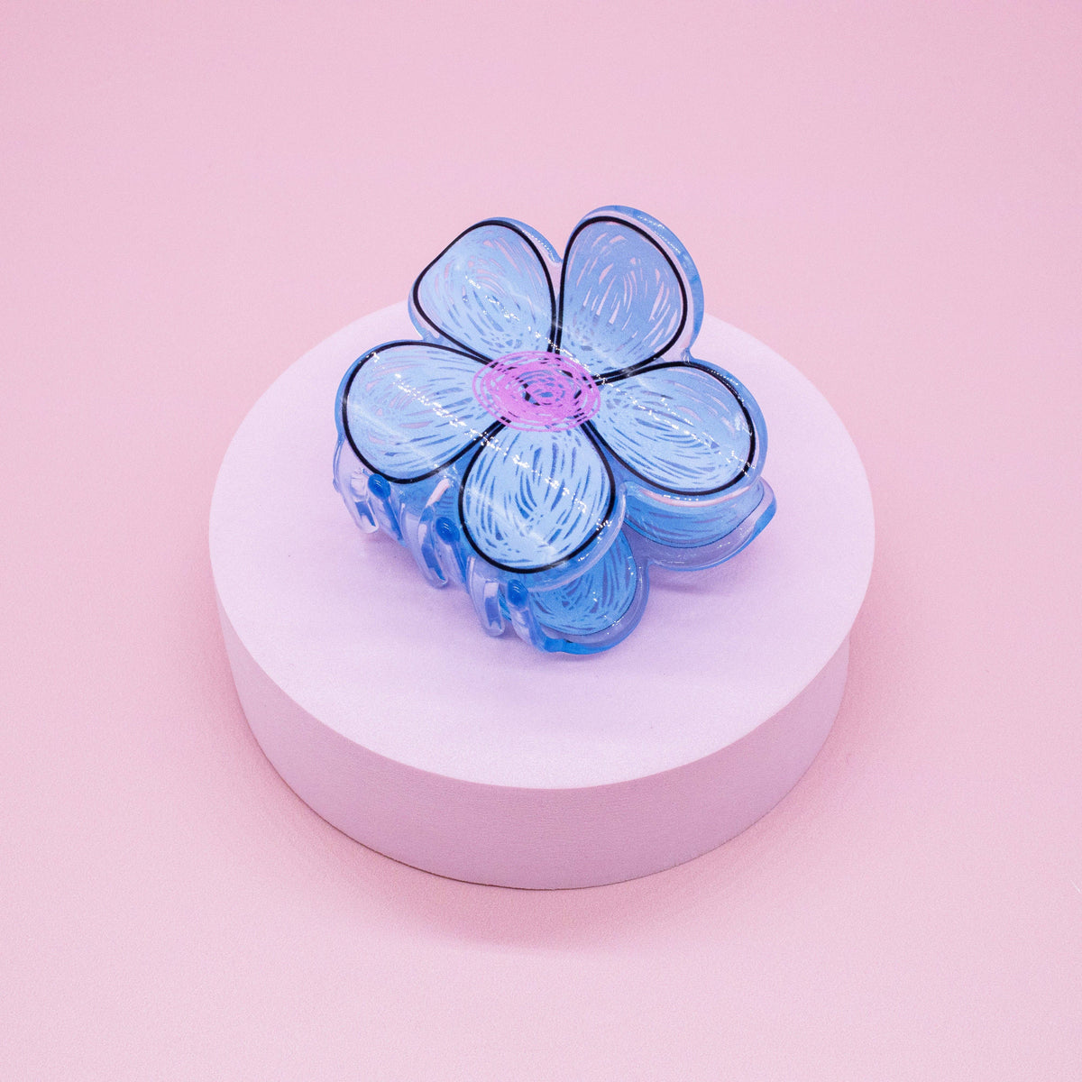 FULL MOOD blue daisy flower hair claw clip made of glossy acrylic with a pink center on a pink pedestal