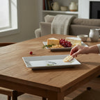 FULL MOOD rectangular porcelain serving platter with blue heron motif on a wooden dining table with cheese and grapes
