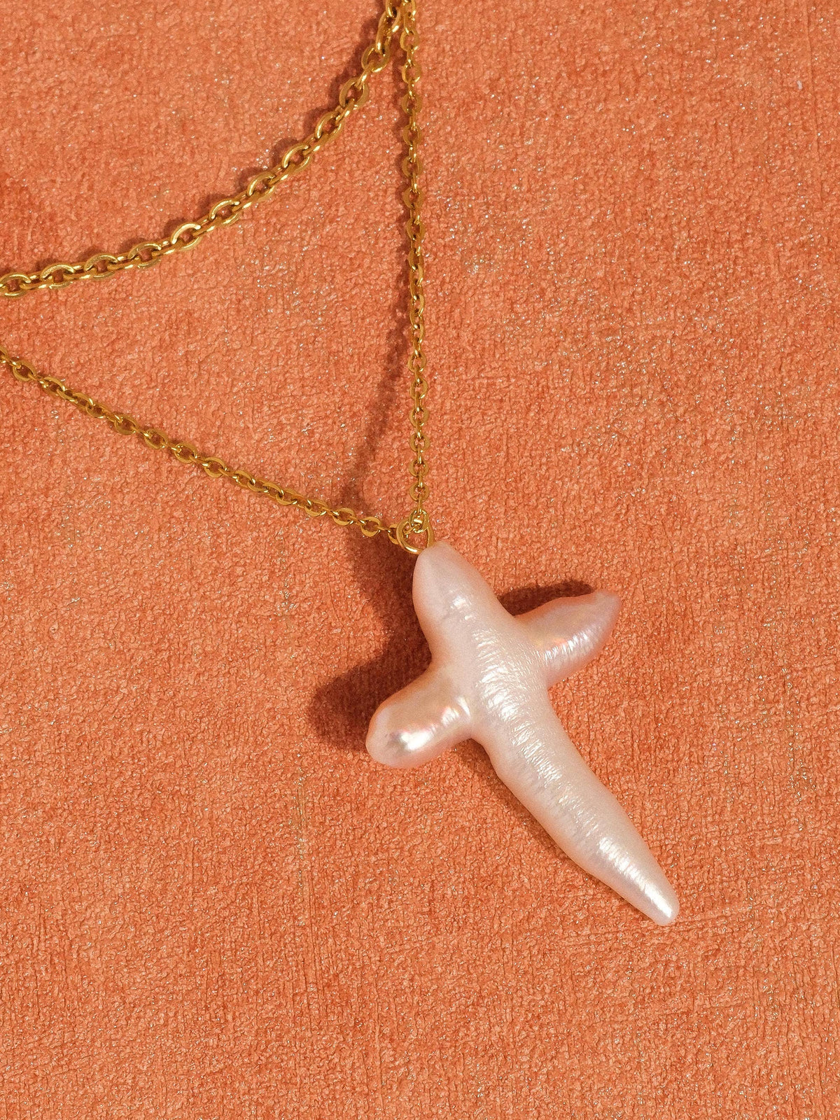 FULL MOOD 18K gold double-layered chain necklace featuring a lustrous freshwater pearl cross pendant on orange background