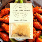 FULL MOOD Hannah's Hot Buffalo seasoning dip mix packet resting on a wooden platter of spicy buffalo chicken wings.