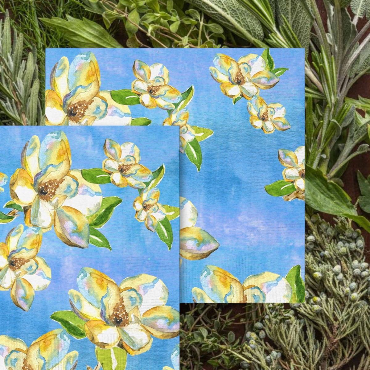 FULL MOOD cocktail napkins featuring a watercolor magnolia blossom print in cream and yellow on a cerulean blue base.