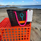 FULL MOOD Mini Market tote bag in black open-grid plastic with bright pink rope handles, sitting on an orange crate.
