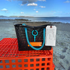 FULL MOOD Mini Market tote bag in black open-grid plastic with bright blue rope handles, set on an orange crate.
