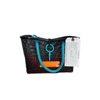 FULL MOOD Mini Market tote bag in black open-grid plastic with blue rope handles, set on an orange crate at the beach.