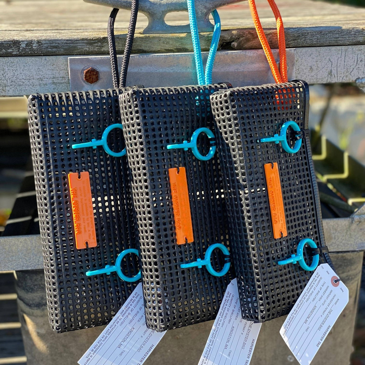 FULL MOOD The Clutch oyster bags in black mesh with vibrant blue and orange rope handles and plastic toggles.