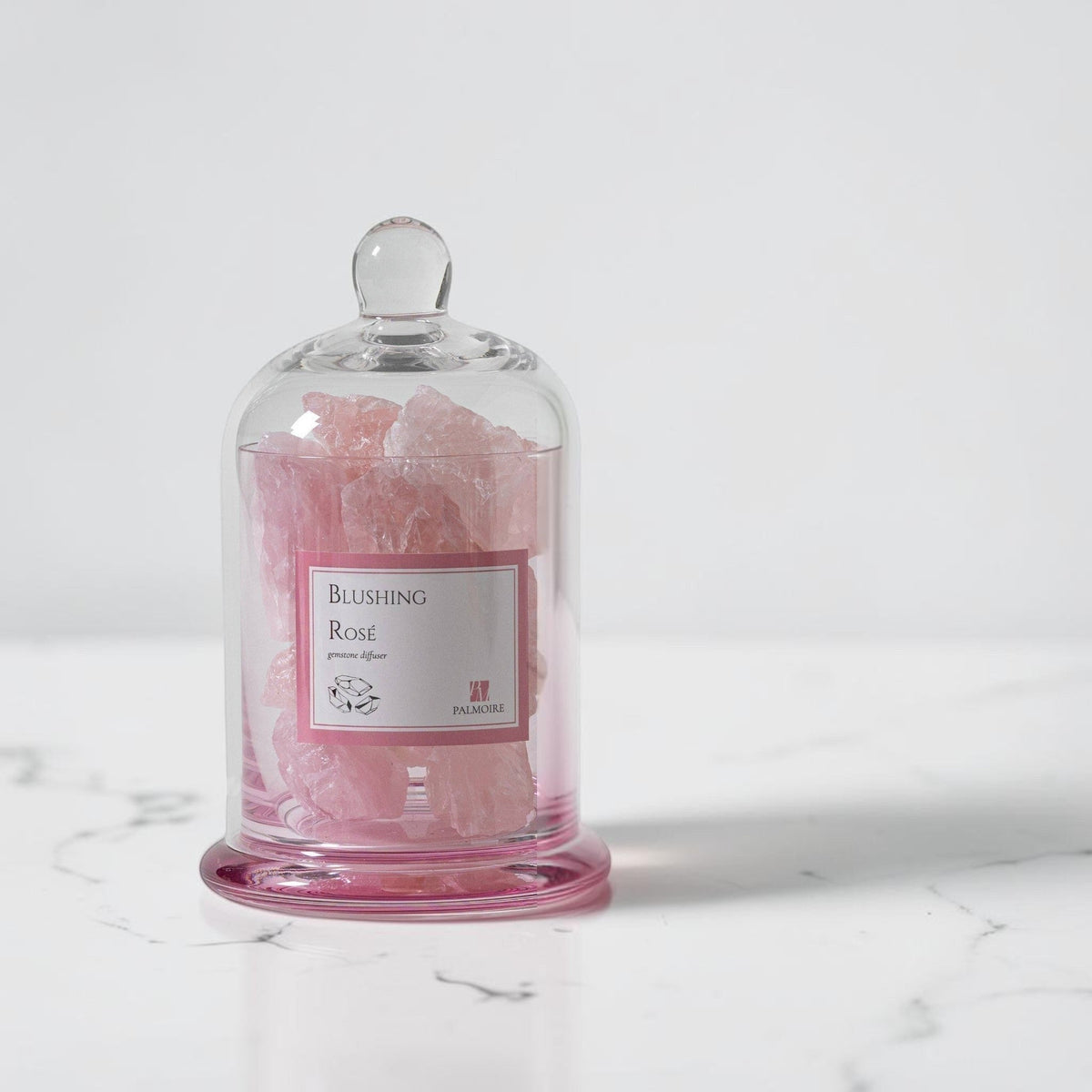 FULL MOOD PALMOIRE Blushing Rose gemstone diffuser with pink crystals inside a glass cloche on a marble surface.