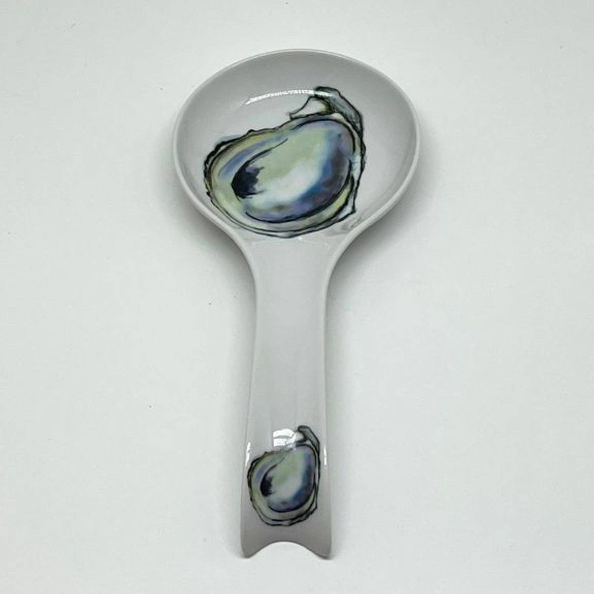 FULL MOOD porcelain oyster spoon rest with a white finish and blue and green oyster shell illustrations.