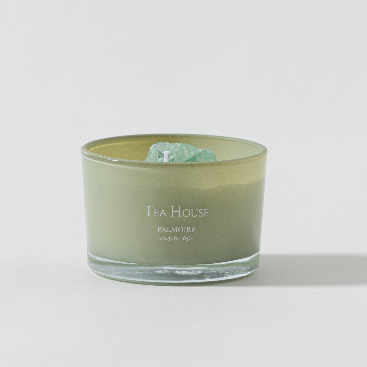 FULL MOOD Tea House soy wax candle in a sage green glass jar topped with a raw green gemstone on a white background.