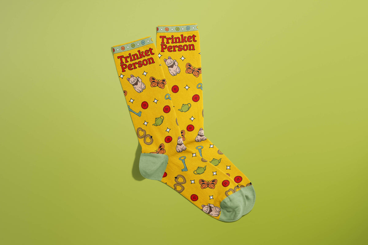 FULL MOOD yellow crew socks featuring a Trinket Person print with tiny ceramic frogs, buttons, and keys on green background