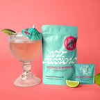 FULL MOOD Stir Sessions watermelon margarita cocktail mix packet next to a prepared drink with lime and umbrella