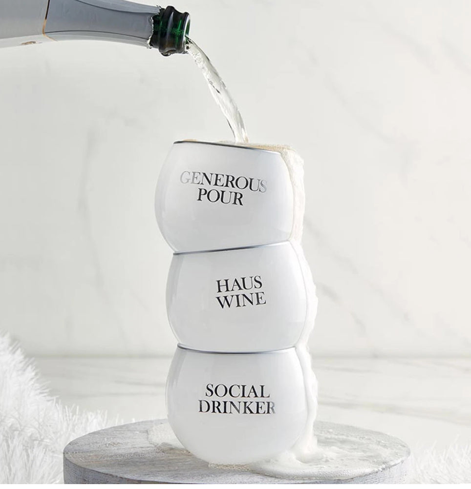 FULL MOOD white stemless wine tumblers stacked with black typography and silver rims being filled with wine