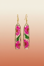Pressed dried flower dangle earrings hanging against terracotta background