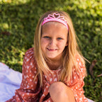 girl with pink tiara headband sittin on grass