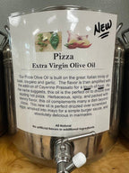 A stainless steel dispenser bottle of Pizza Extra Virgin Olive Oil with a large white product label showing ingredients and descriptive text, set on a wooden surface.